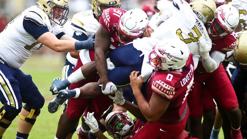 Florida State defenders, including defensive tackle Fabien Lovett (0), lift Georgia Tech running back Hassan Hall (3) off the ground as he tries to runs the ball in the second quarter of an NCAA college football game Saturday, Oct. 29, 2022, in Tallahassee, Fla. (AP Photo/Phil Sears)